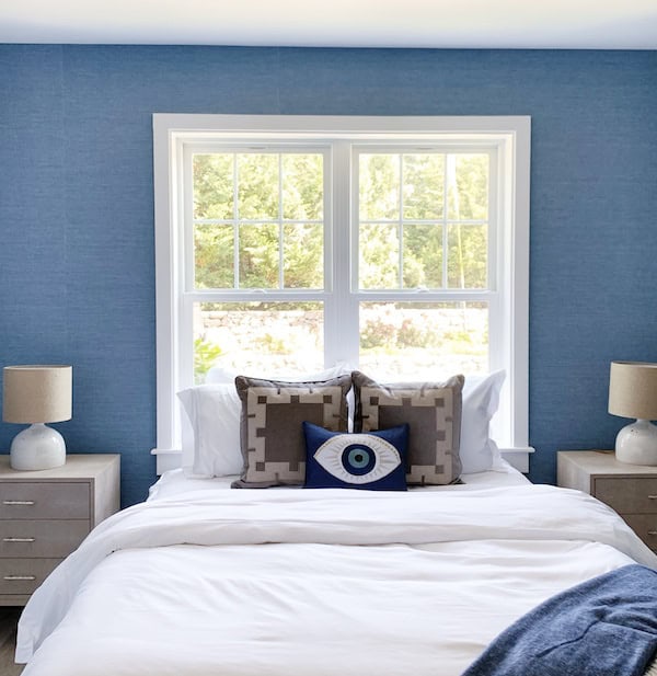 blue bedroom with white bed in front of window.