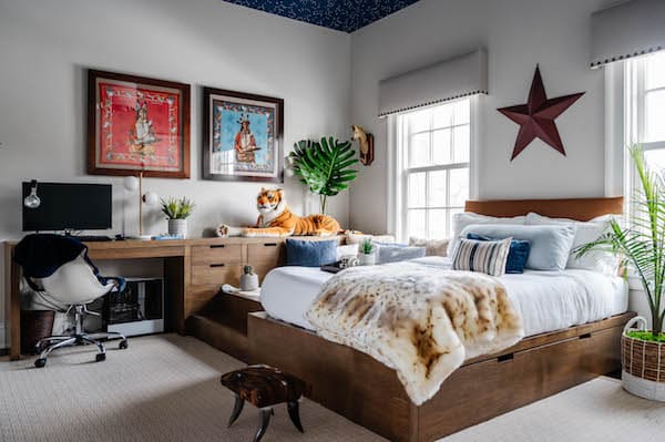 bed placed in teen boys room in front of window wall.