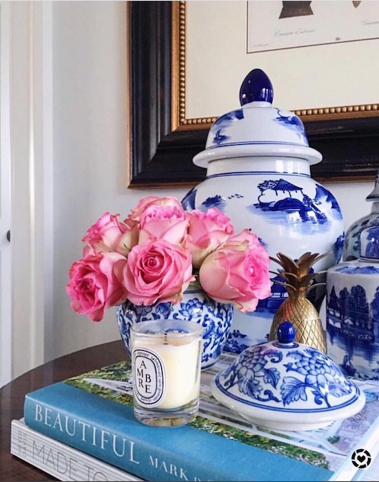 blue and white vase with pink flowers and scented candle