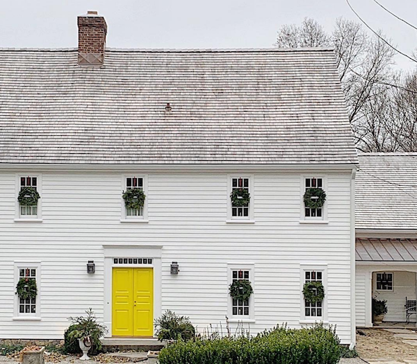 white clapboard house with Christmas wreaths and bright yellow front door