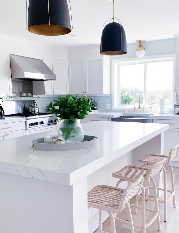 white walls in kitchen with white cabinets and black pendant lights.