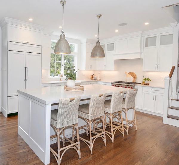 all white kitchen with wood floors and rattan stools