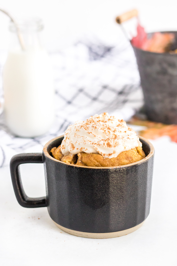 keto pumpkin mug cake with whipped cream in black ceramic mug