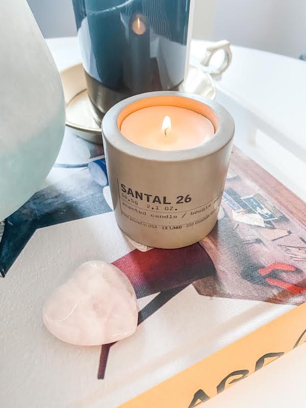 small candle on table next to heart shape paper weight.