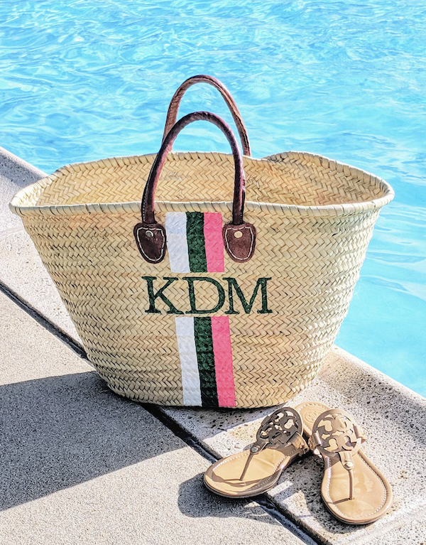 monogram tote at edge of blue pool with sandals.