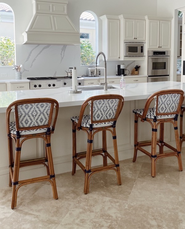 cream painted kitchen cabinets with white counters and wooden counter stools