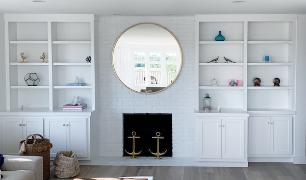 white beach house family room with painted brick firplace and bookcases.