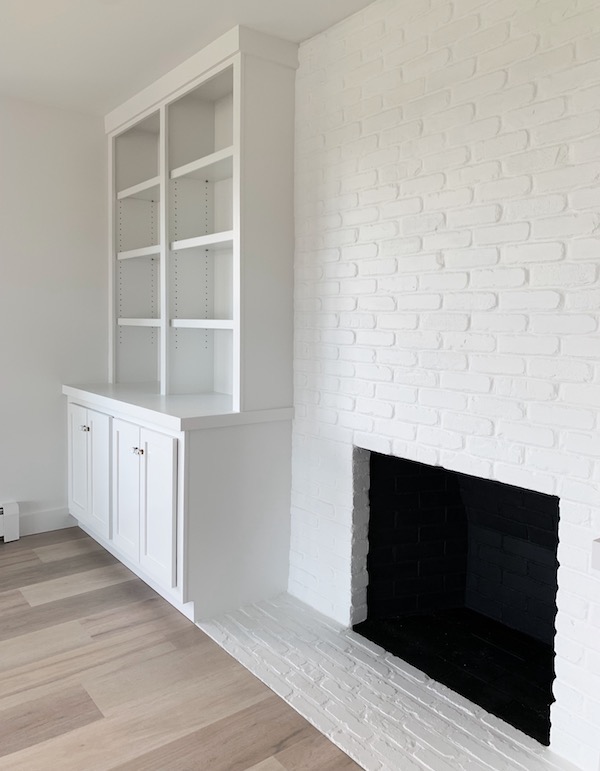 finished white painted fireplace with black painted interior and white painted bookcases.