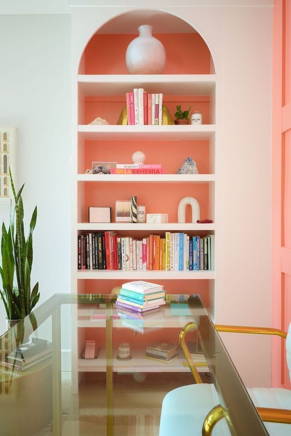 arched bookcase painted a colorful pale coral.