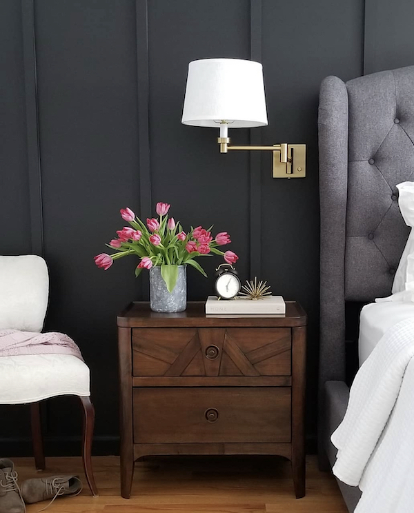 black painted bedroom walls with nightstand and light.