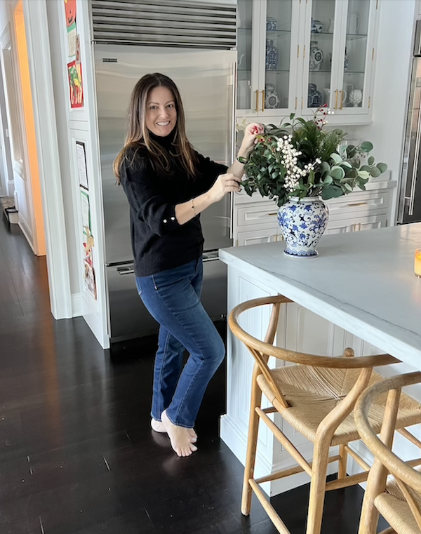 woman wearing jeans and black sweater in a kitchen.