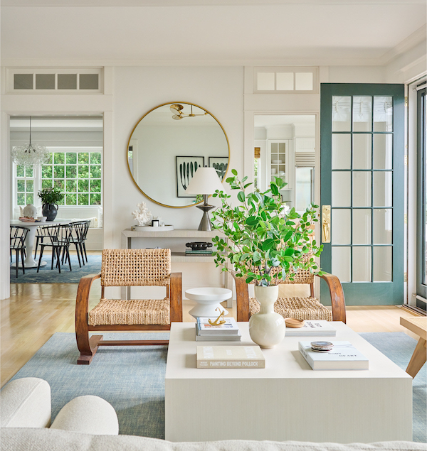 living room with square coffee table and round mirror, two rattan chairs.