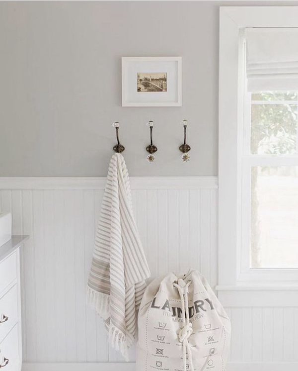 half wall in bathroom with wainscotting and hooks.