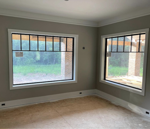 new build construction project with freshly painted gray walls and two new windows.