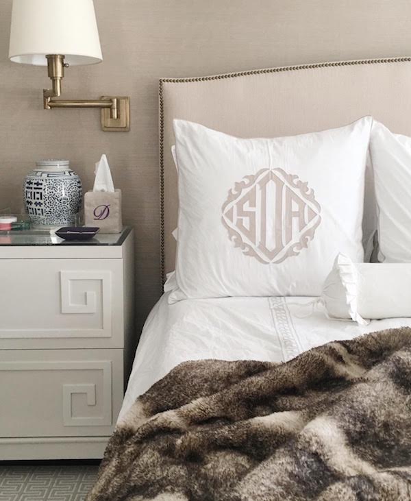 Bedroom with monogram pillow on bed and faux fur blanket.