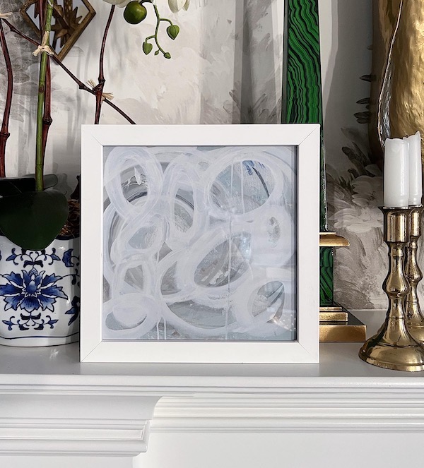 small framed abstract art on a fireplace mantel. 