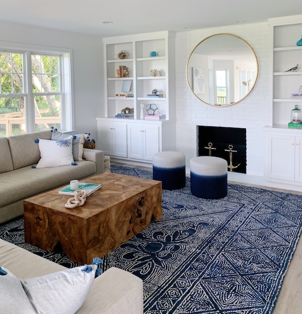 family room with fireplace and bookshelves round mirror and navy rug.