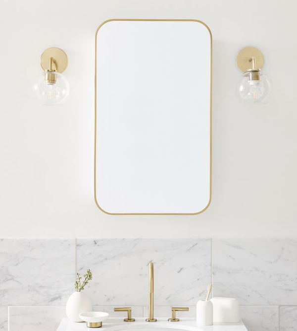 white bathroom with gold frame mirror and sconces.