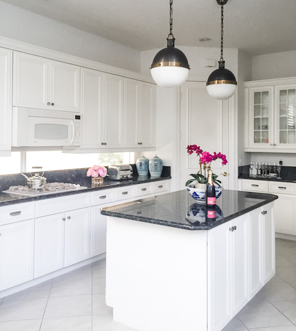 white kitchen with spray painted cabinets and dark marble counters. 