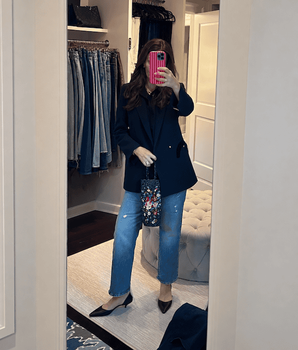 Navy double breasted blazer over black shirt and light wash jeans with beaded bag.