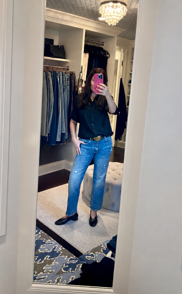 women in closet wearing black top and jeans.